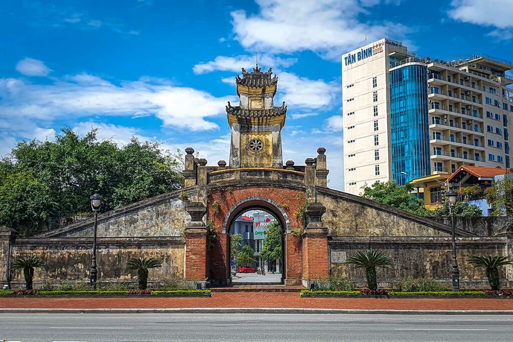 De historische toegangspoort van de Dong Hoi Citadel, gebouwd in de Nguyen-dynastie, met moderne gebouwen op de achtergrond.