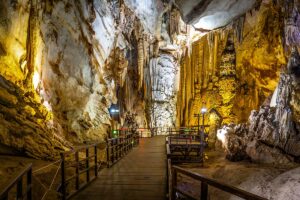 Houten loopbrug in Paradise Cave in Phong Nha, met zicht op hoge grotÂwanden en langgerekte stalactieten langs de route.
