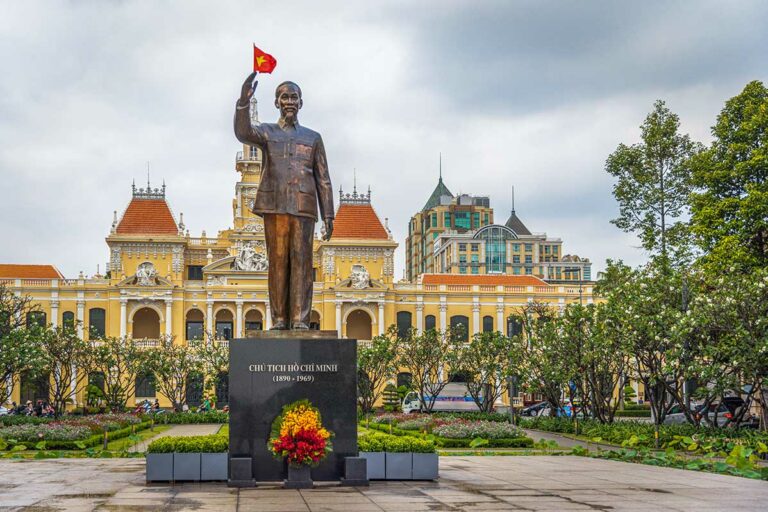 Standbeeld van Ho Chi Minh op een plein in Ho Chi Minh City, met op de achtergrond het voormalige stadhuis, tegenwoordig het People’s Committee Building.