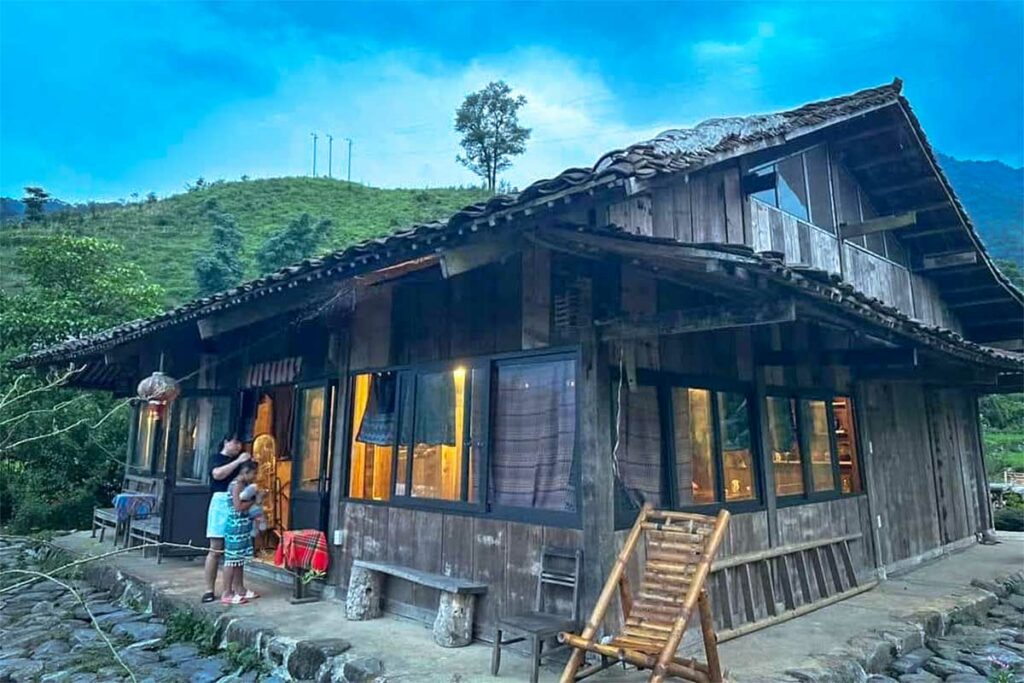 Traditionele houten homestay nabij Phia Oac National Park waar reizigers overnachten in een landelijke omgeving met heuvels en bossen op de achtergrond.