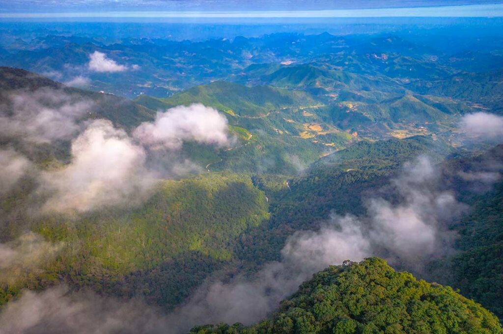 Luchtfoto van Phia Oac National Park met uitgestrekte bossen, heuvels en valleien deels bedekt door wolken in het noorden van Vietnam.