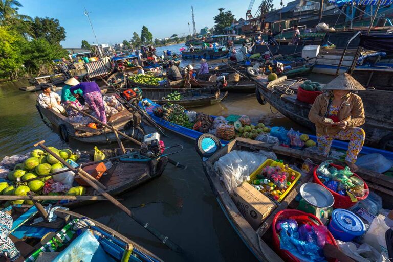 Drukte op de Phong Dien drijvende markt in de Mekong Delta, met houten boten vol fruit en lokale handelaren die hun producten vanaf het water verkopen