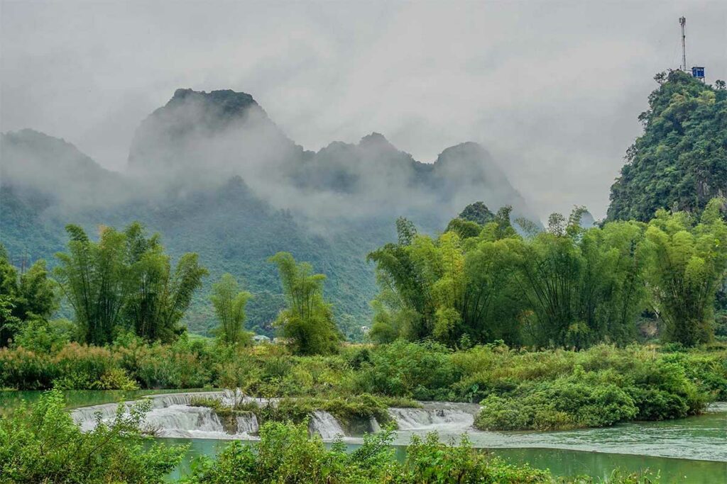 Kleine waterval en stroomversnelling in Phong Nam Valley, omgeven door bamboe en groene heuvels in Cao Bang