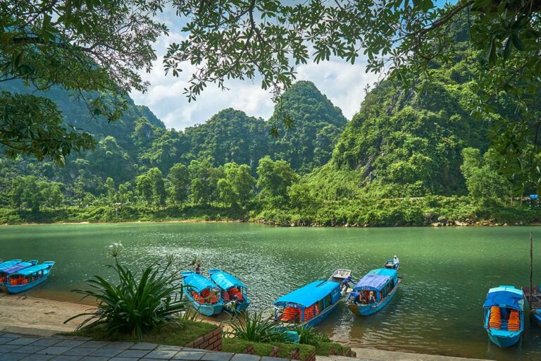 Boten aangemeerd bij het Phong Nha Cave Boat Station aan de Son-rivier, startpunt van de boottocht naar de grot.