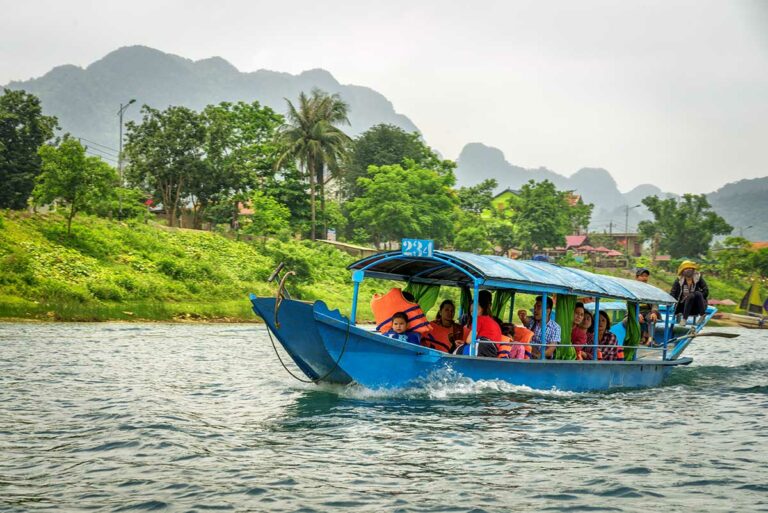 Boot met bezoekers op de Son-rivier bij Phong Nha, onderdeel van de boottocht richting Phong Nha Cave door het landelijke landschap.