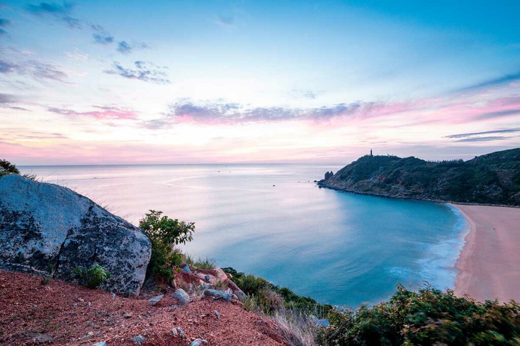 Rustige kustlijn in Phu Yen bij zonsopkomst met uitzicht over zee en heuvels, een mooie locatie voor landschapsfotografie in Zuid-Centraal-Vietnam.