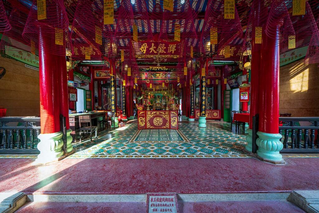 Interieur van Phuc Kien Assembly Hall in Hoi An met rood altaar, wierookspiralen en kleurrijke Chinese decoraties