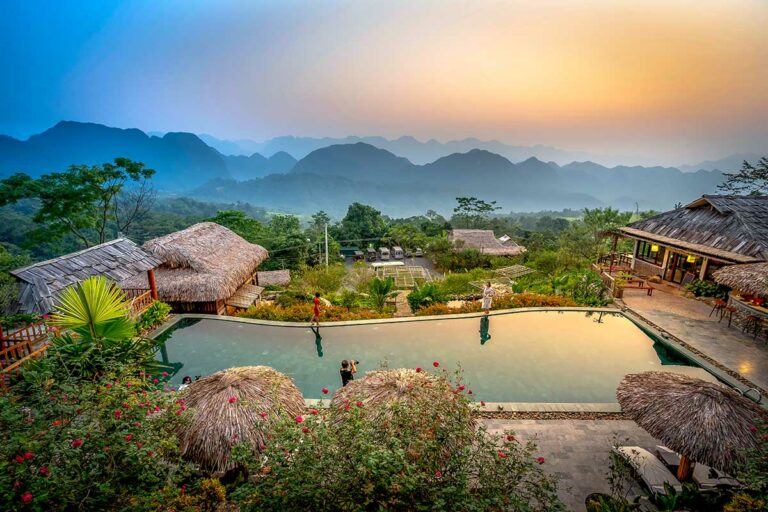 Uitzicht vanaf Pu Luong Eco Garden over de groene vallei en bergketens, met traditionele bungalows en rijstvelden in de omgeving