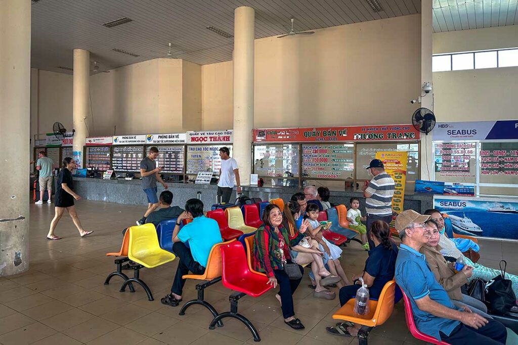 Reizigers wachten in de ferryterminal van Rach Gia bij loketten voor tickets naar de eilanden