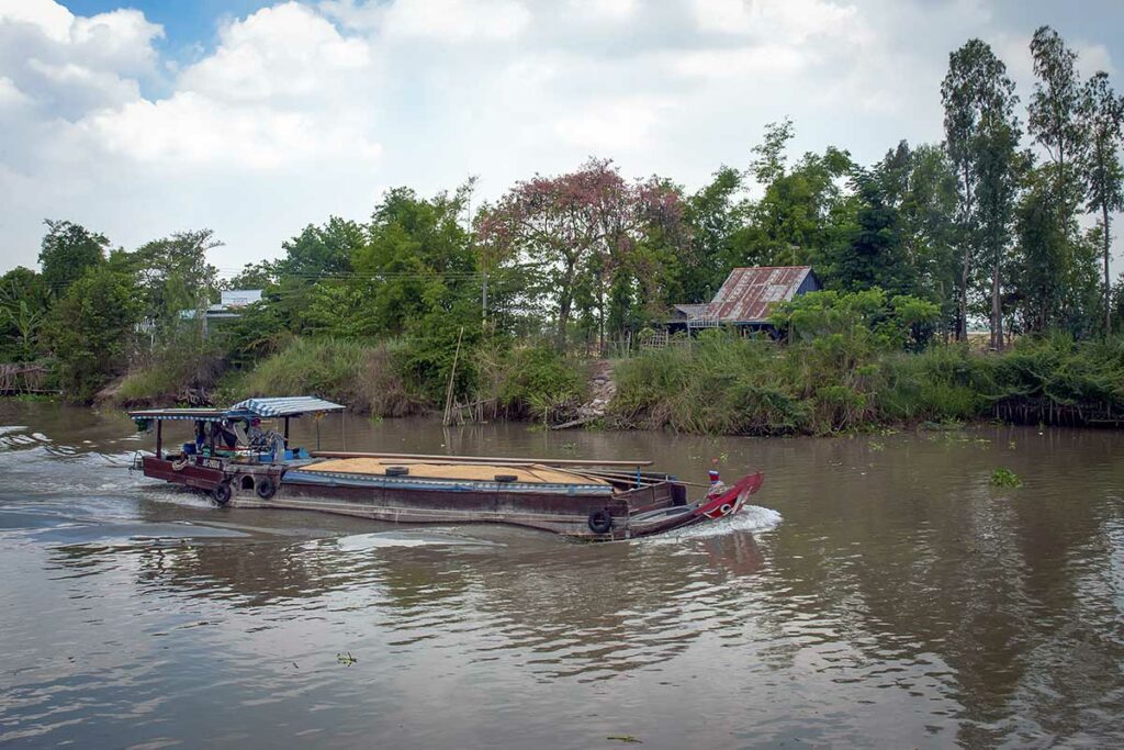 Lokale boot vaart over een rivier bij Rach Gia langs huizen en groen in de Mekong Delta