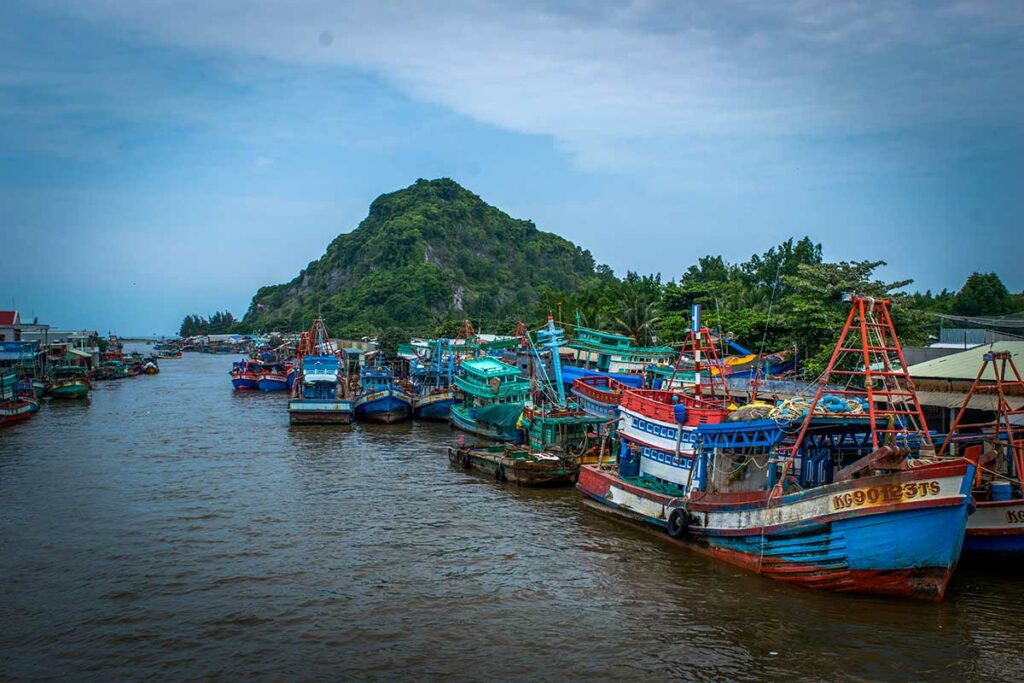 Kleurrijke vissersboten in de haven van Rach Gia met heuvel op de achtergrond in Kien Giang
