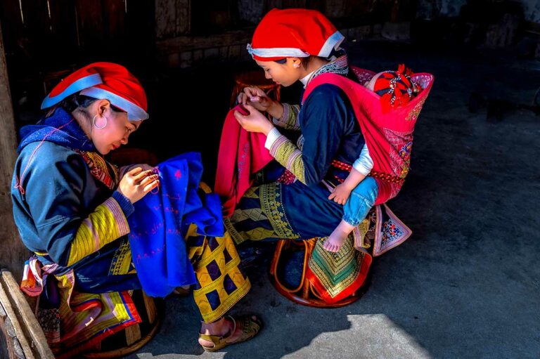 Red Dao vrouwen werken aan traditioneel borduurwerk in Sapa, een intiem moment voor portret- en culturele fotografie in Noord-Vietnam.