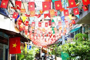 Smalle straat in Vietnam met rijen Vietnamese vlaggen en feestversiering ter gelegenheid van Reunification Day, de nationale Herenigingsdag.