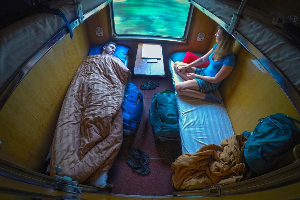 Reizigers liggend in 4 persoons slaapcoupé in Vietnamese nachttrein met bagage onder de bedden