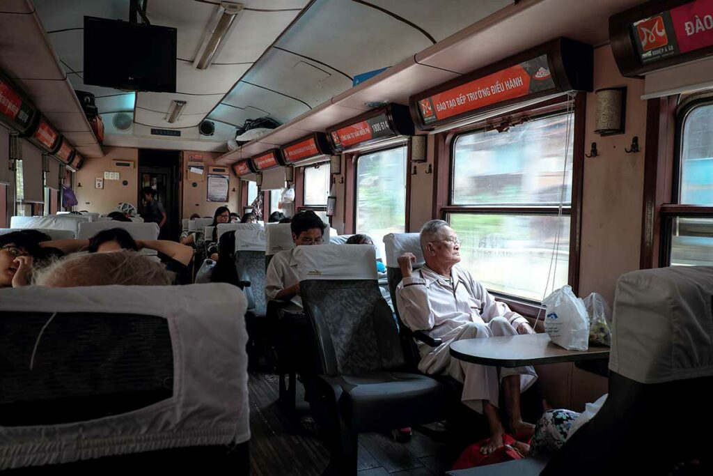 Interieur van soft seat wagon in Vietnamese trein met passagiers zittend bij het raam