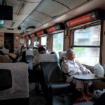 Interieur van soft seat wagon in Vietnamese trein met passagiers zittend bij het raam