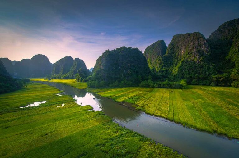 Rijstvelden van Tam Coc in Ninh Binh gezien vanuit de lucht, met rivier, kalkstenen bergen en groene landbouwgronden in het karstlandschap