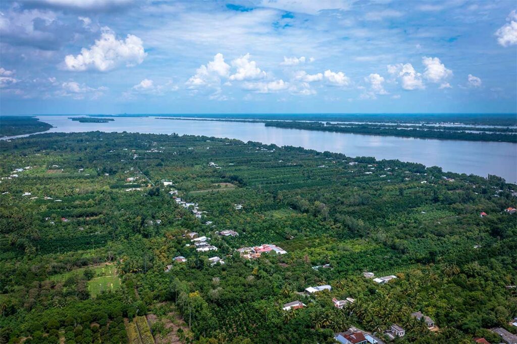 Luchtfoto van Tan Quy-eiland in Tra Vinh met groene boomgaarden, smalle kanalen en de brede Hau-rivier in de Mekongdelta