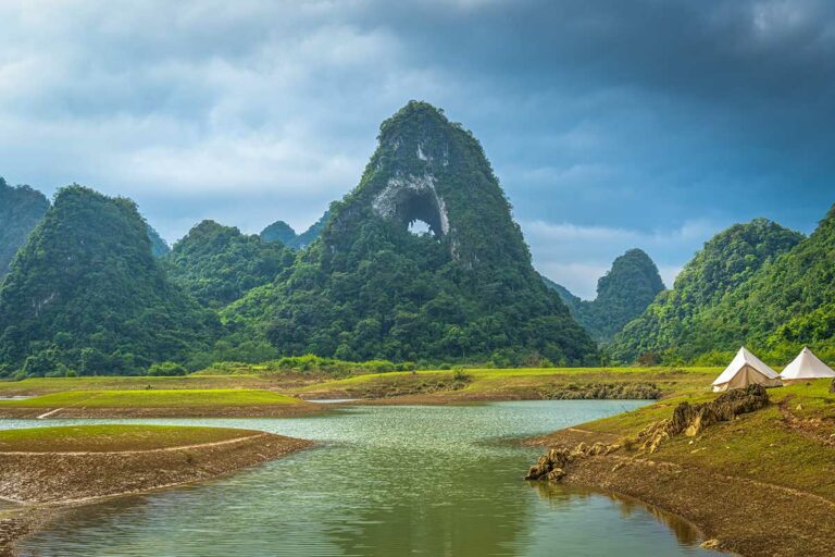 Kampeerplek bij Angel Eye Mountain met tenten langs het water, omringd door karstbergen en stilte in het landschap van Cao Bang.