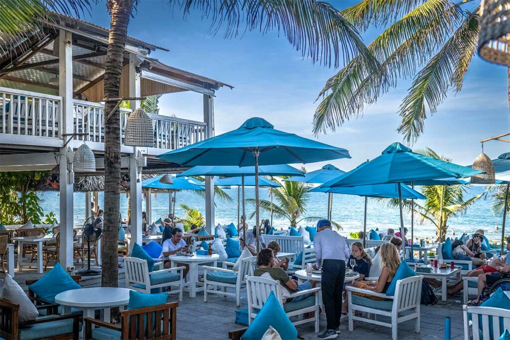 The Deck House strandrestaurant bij An Bang Beach in Hoi An met blauwe parasols en zitplaatsen direct aan zee