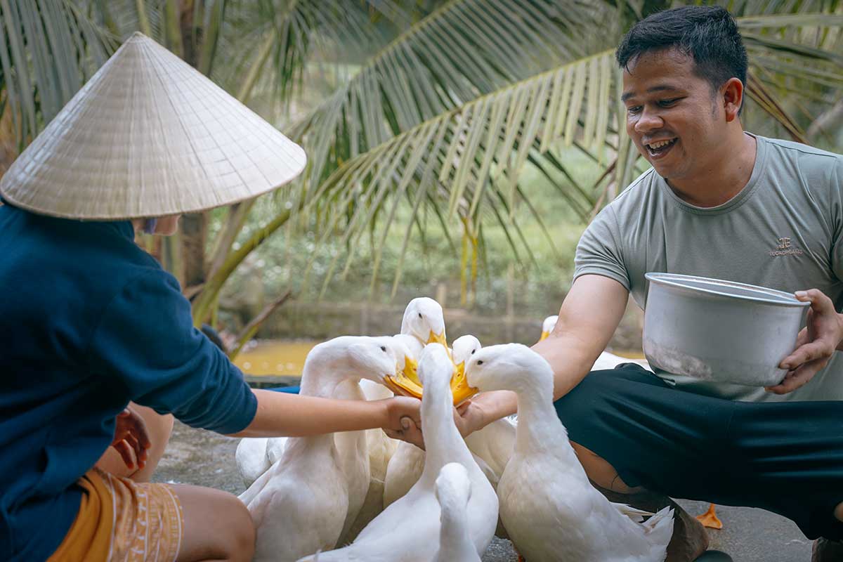 Lokale boer en bezoeker voeren samen eenden op de eendenboerderij van The Duck Stop in Phong Nha.
