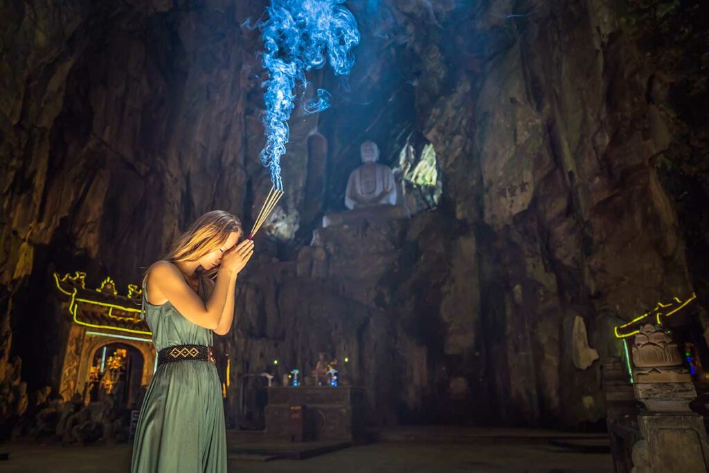 Buitenlandse reiziger die wierook brandt in een grot-tempel in Vietnam, een moment van gebed binnen de Vietnamese volksreligie waarbij respect voor lokale spirituele tradities centraal staat