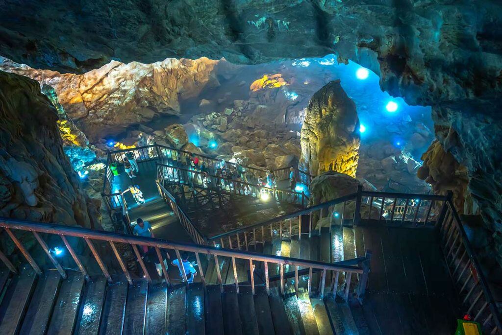 Houten trap en loopbrug net binnen de ingang van Paradise Cave (Thien Duong), waar bezoekers afdalen in de grot langs verlichte rotsformaties.