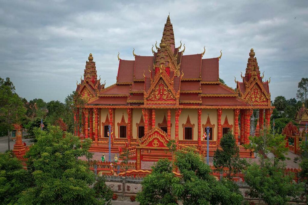 Tuk Prasat Khmer-tempel in Soc Trang met rood-gouden decoraties en sierlijke torens omringd door groen