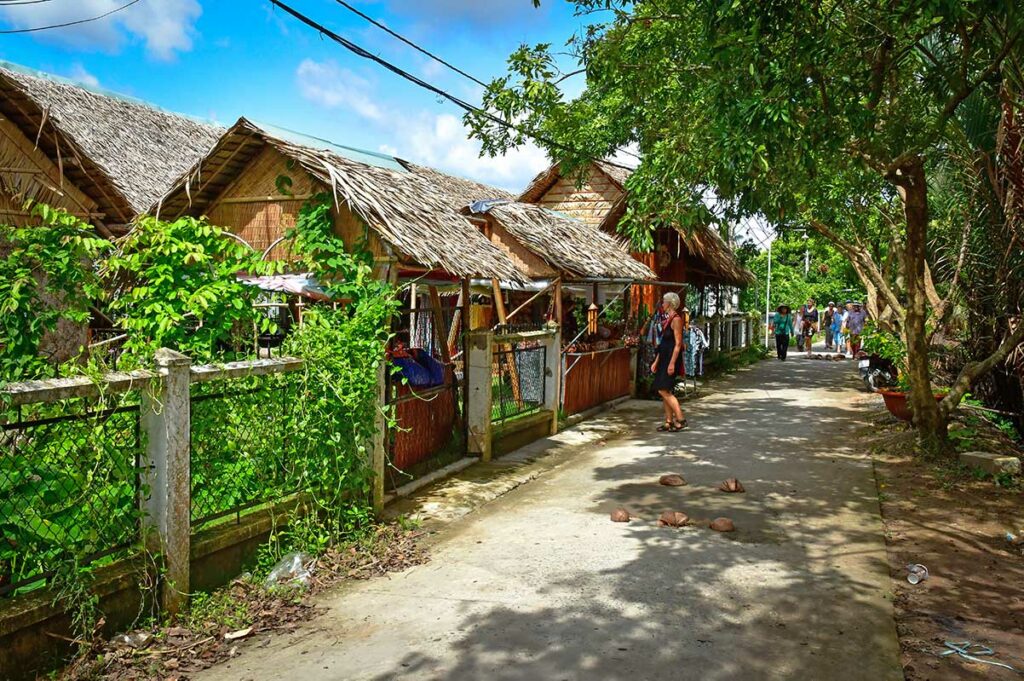 Lokale straat op Unicorn Island bij My Tho Mekong Delta met traditionele huizen en reizigers die wandelen