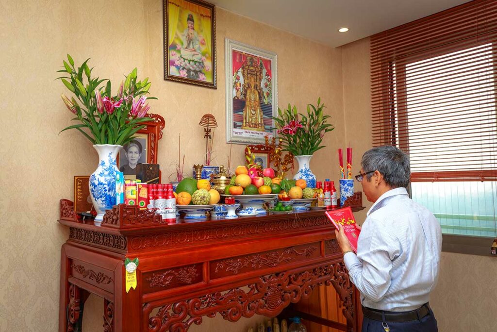 Man die bidt bij een familiealtaar in huis, een centraal onderdeel van voorouderverering en dagelijks geloof binnen de Vietnamese volksreligie