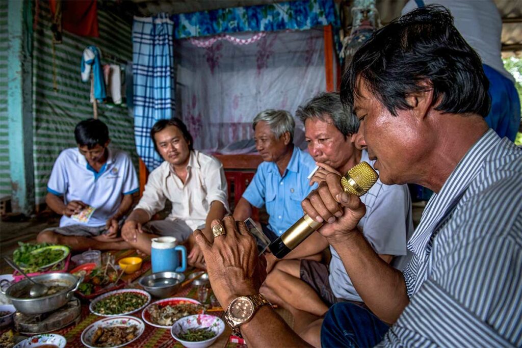 Vietnamese vrienden zingen karaoke tijdens een gezamenlijke maaltijd thuis, typisch voorbeeld van sociale karaoke in Vietnam