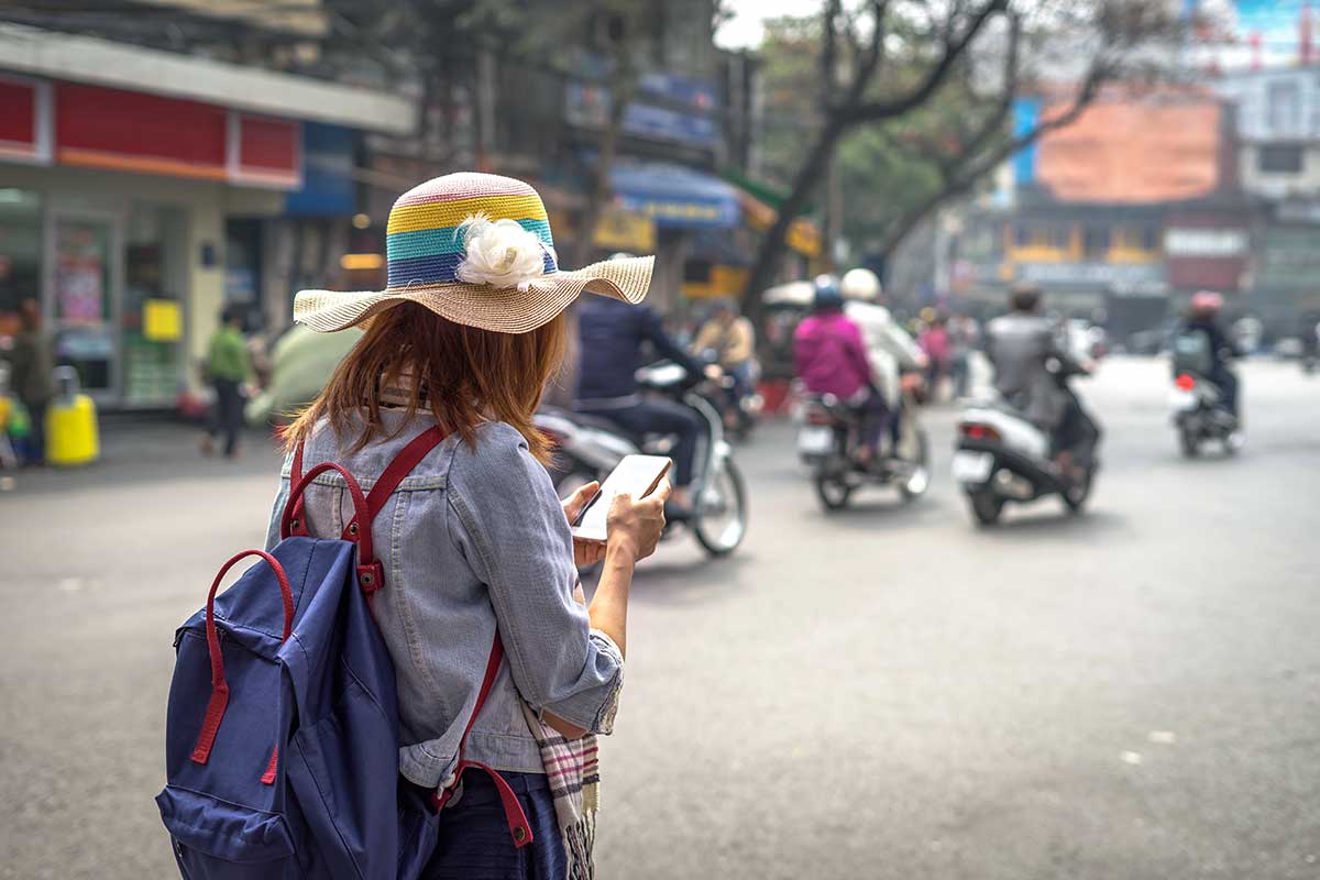 Toerist met rugzak gebruikt smartphone op straat in Vietnam, ideaal beeld voor eSIM Vietnam en mobiel internet tijdens het reizen