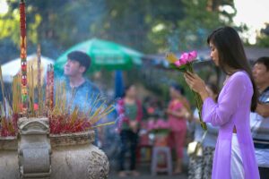 Vrouw die wierook en bloemen offert bij een tempelaltaar tijdens een religieus ritueel, typerend voor de Vietnamese volksreligie en spirituele tradities
