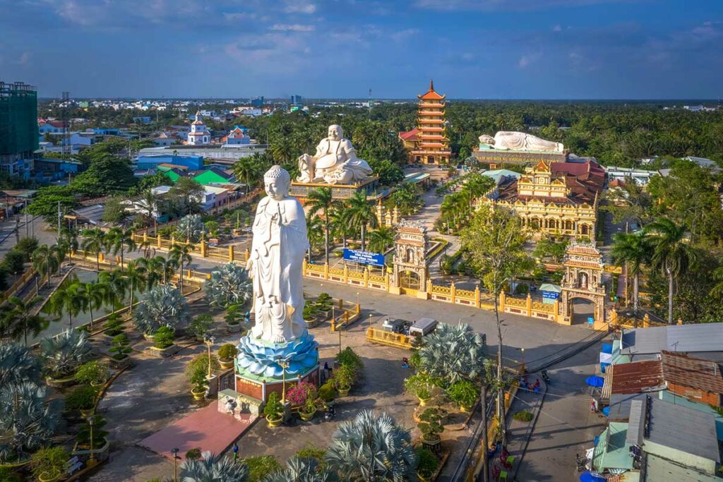 Luchtfoto van Vinh Trang Pagoda in My Tho met staande Amitabha Boeddha, zittende Maitreya, liggende Shakyamuni en de zeven verdiepingen tellende toren tussen palmbomen