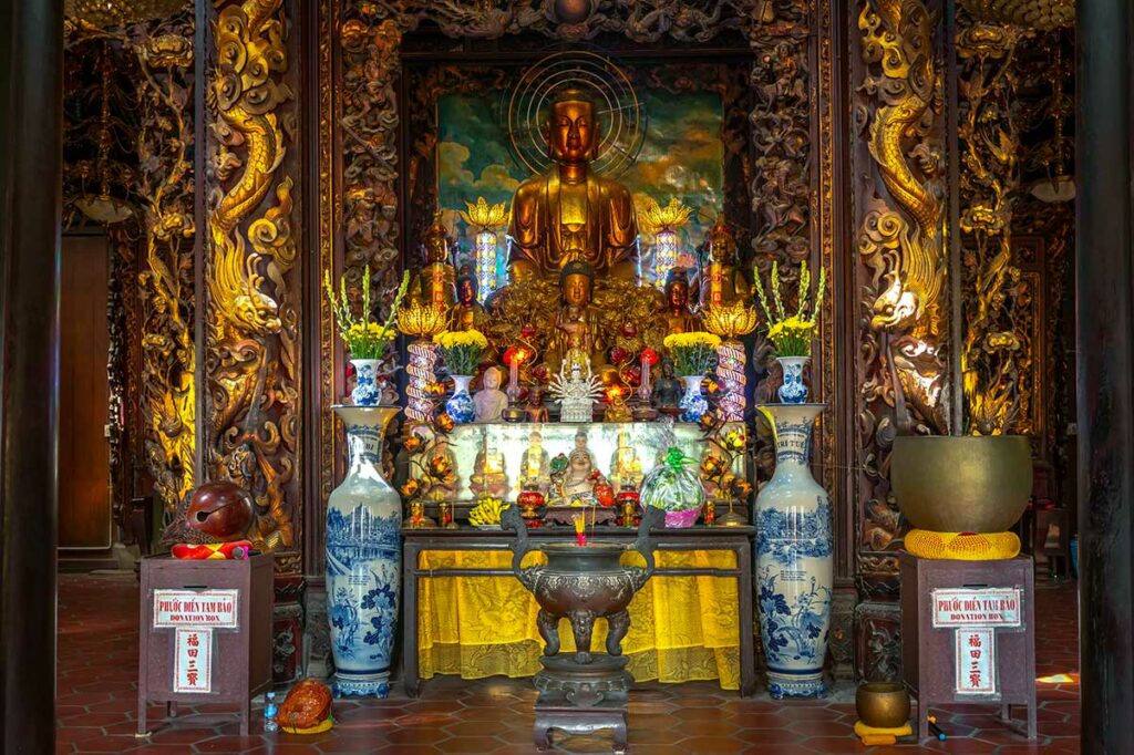 Rijk versierd altaar met Boeddhabeelden en drakensnijwerk in de hoofdtempel van Vinh Trang Pagoda in My Tho