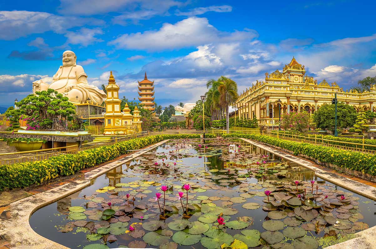 Lotusvijver bij Vinh Trang Pagoda in de Mekongdelta met Maitreya Boeddha en hoofdtempel op de achtergrond
