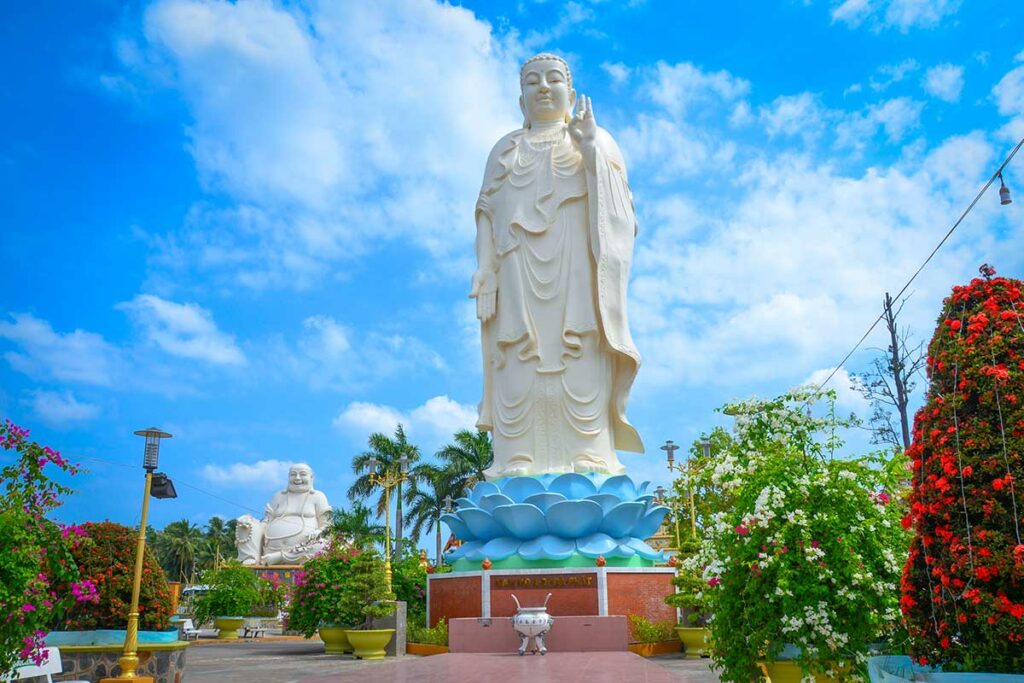 Staande Amitabha Boeddha van 18 meter hoog bij Vinh Trang Pagoda in My Tho met lotusvoet en tuin op de voorgrond