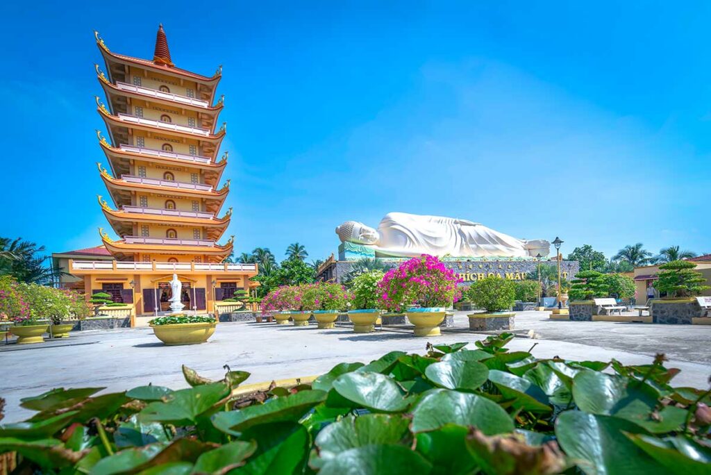 Zeven verdiepingen tellende toren en liggende Shakyamuni Boeddha bij Vinh Trang Pagoda in My Tho met bloementuin op de voorgrond