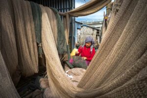Lokale vrouw repareert visnetten tussen hangende netten in visserswijk in Ca Mau Mekong Delta Vietnam