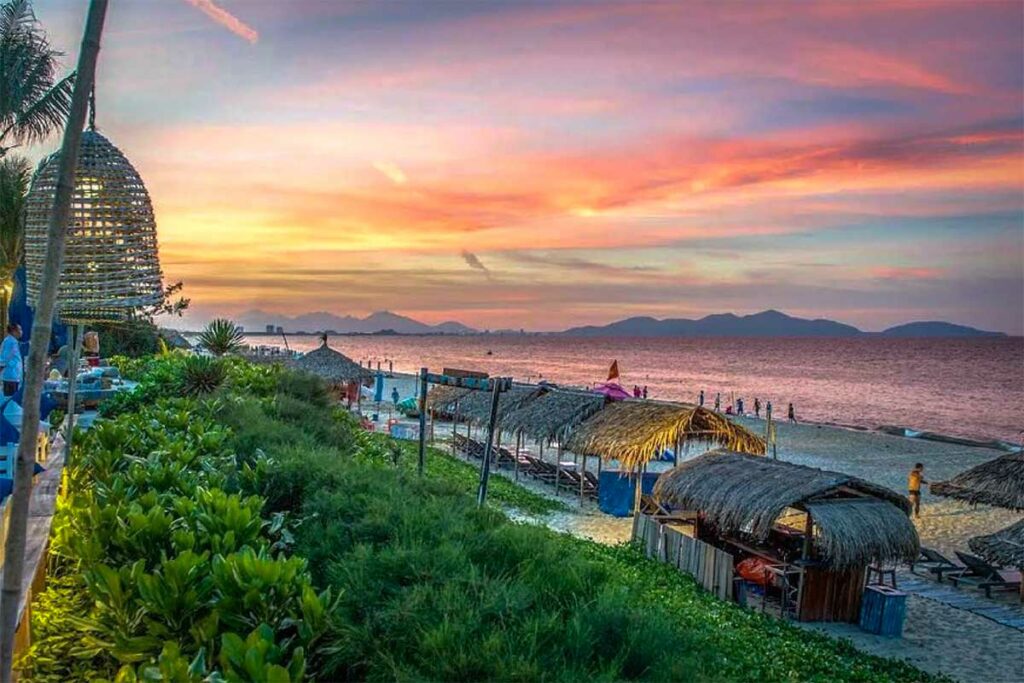 Zonsondergang bij An Bang Beach in Hoi An met strandhutten en kleurrijke avondlucht