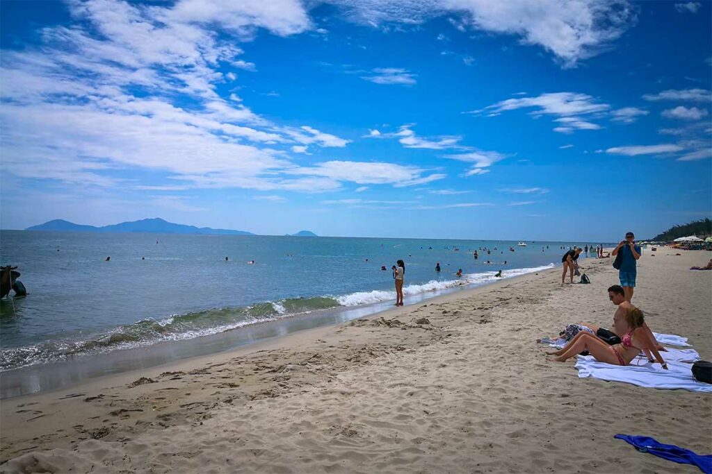 Mensen zwemmen en ontspannen op het strand van An Bang Beach bij Hoi An met zee en eilanden op de achtergrond