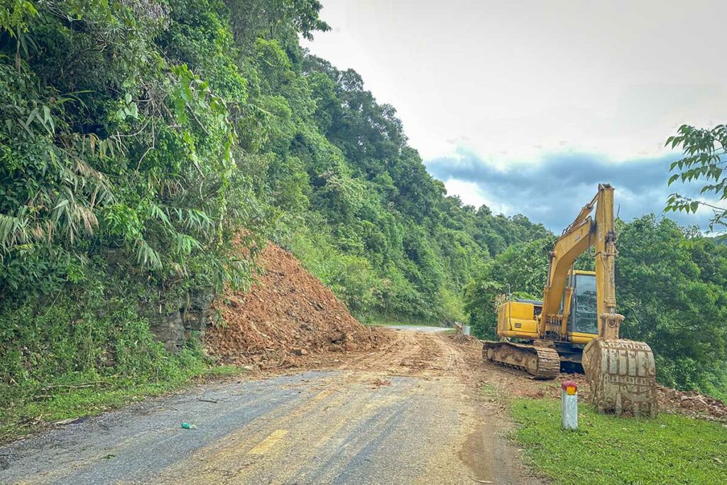 Graafmachine ruimt een aardverschuiving op die een bergweg in Vietnam blokkeert na zware regen tijdens een tyfoon of tropische storm
