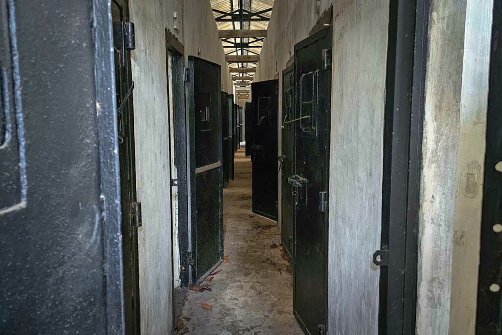 Gang met smalle cellen en zware deuren in de American Tiger Cages van Phu Binh Prison op Con Dao, beruchte gevangenis uit de Vietnamoorlog