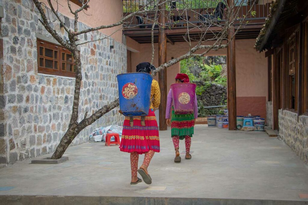 Hmong vrouwen lopen door de binnenplaats van Ha Giang Aya Lodge tijdens de bouwfase van de lodge van Local Vietnam in de bergen van Ha Giang