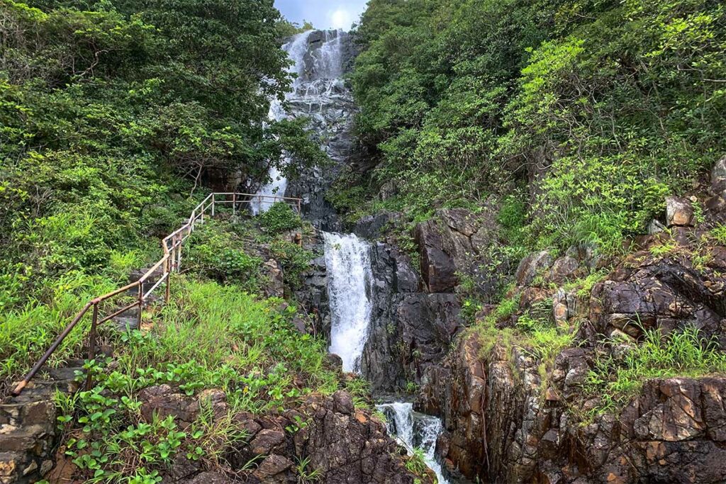 Waterval langs de trekkingroute naar Bai Bang in Con Dao National Park, omgeven door rotsen en dichte jungle