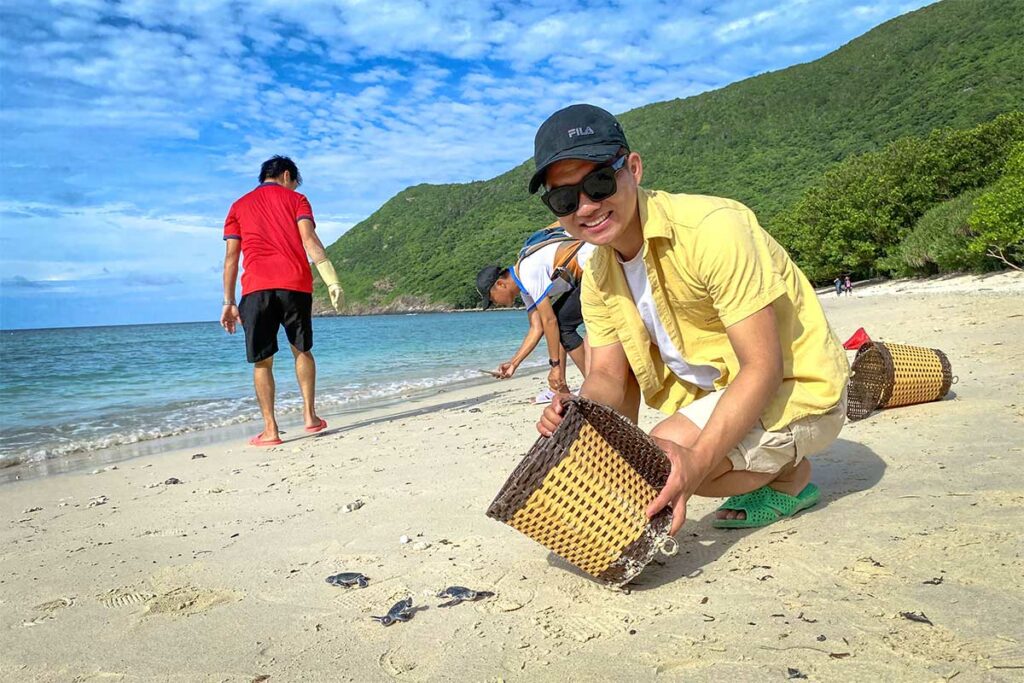 Bezoekers laten babyschildpadden vrij op het strand van Con Dao, terwijl de jonge schildpadjes richting de zee kruipen onder begeleiding van rangers.