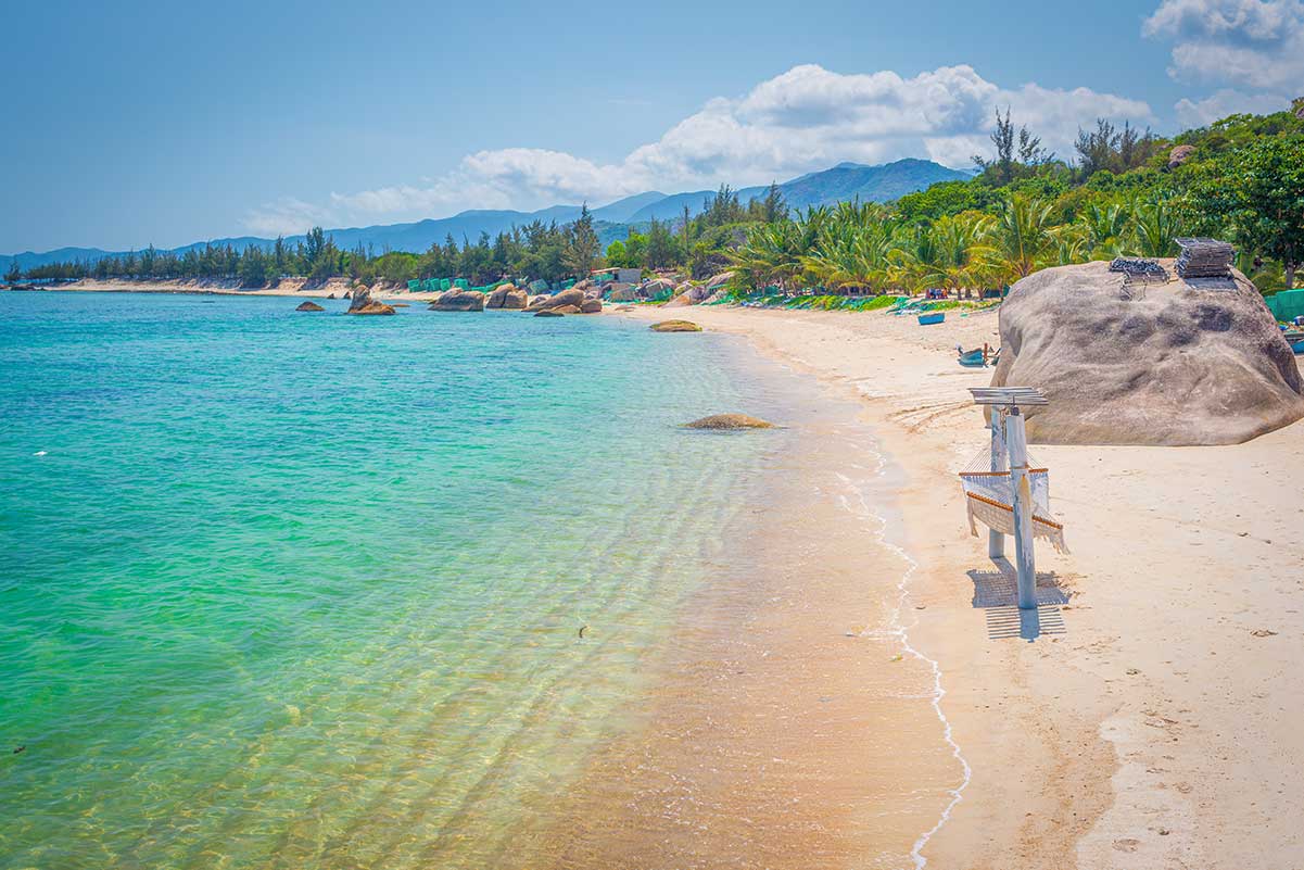 Rustig strand bij Cam Ranh met helder water, zandstrand en palmbomen langs de kust.