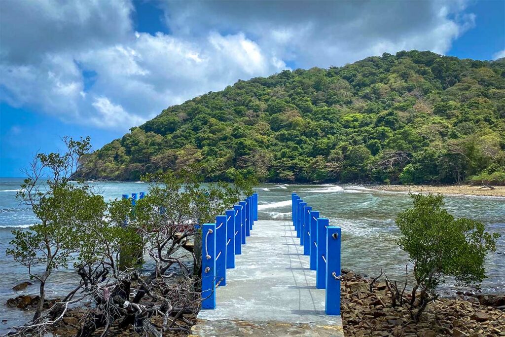 Pier bij Dat Tham Beach in Con Dao National Park met uitzicht op zee en beboste heuvels langs de kust