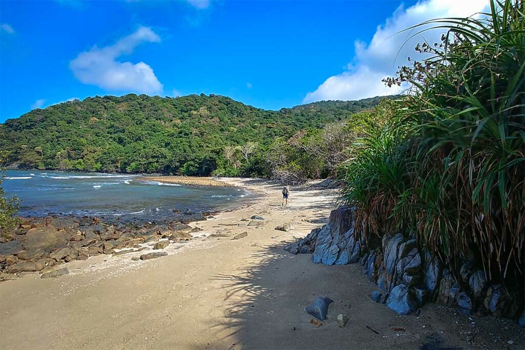 Strand bij Dat Tham Beach in Con Dao National Park met rotsachtige kust en jungle op de achtergrond tijdens een trekkingroute
