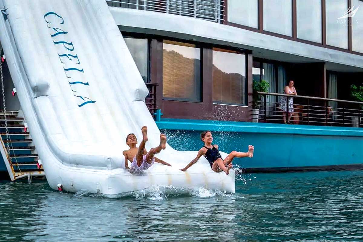 Familierondreis Vietnam met kinderen op Halong Bay cruise terwijl ze van een glijbaan in zee glijden